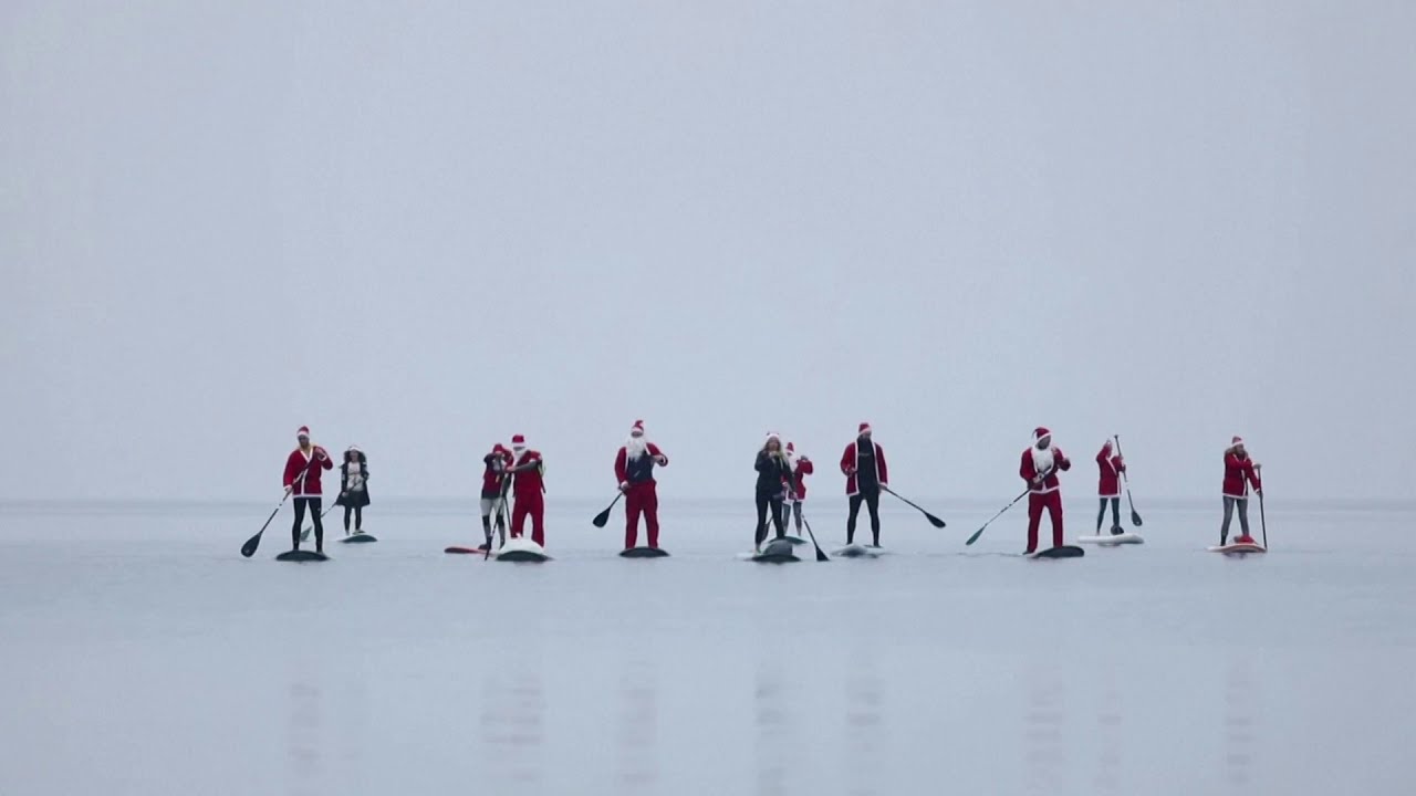 Santas stand-up paddle board on Croatian coast